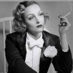 A photo of Marlene Dietrich in a tuxedo, smoking a cigarette.